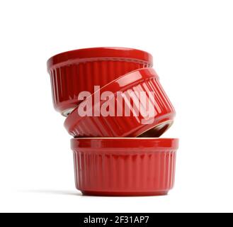 Stack of red ceramic round cupcake baking dishes isolated on white background Stock Photo