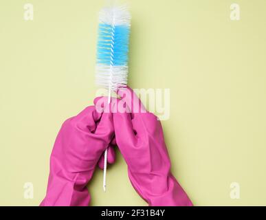 Hand in a rubber glove holds a brush for washing bottles on a green background Stock Photo