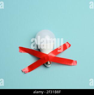 White glass bulb glued with red tape on a blue background Stock Photo