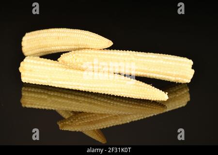 Three bright yellow ripe sweet organic mini mini corn, close-up, on a black background Stock Photo