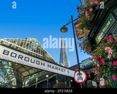 Borough Market sign board London exterior with flowers around 'The Market Porter Pub' with 'a warm welcome' sign over the entrance. LTN Low Traffic Neighbourhood road sign on lamppost. Exterior view international produce market with The Shard behind London Bridge Southwark  London UK Stock Photo