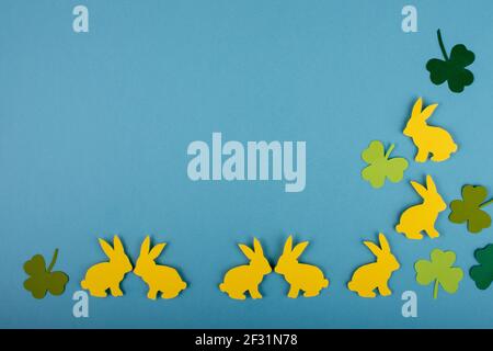 Happy Easter concept. Two side border design with bunnies and clover leaves on blue background. Copy space. Paper cut. Stock Photo
