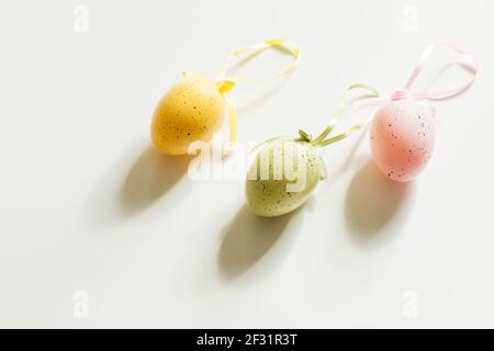 Three colored easter eggs on a white table, bright sunlight. Hope Stock Photo