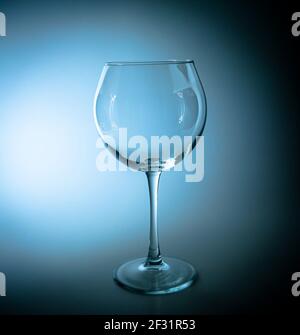 Empty wine glass with a high leg in the dark. Wine glass. Glassware for alcoholic beverages. Glassware for drinks. Transparency. Drinking establishmen Stock Photo