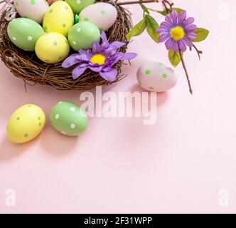 Easter eggs pastel colors in a nest on pink background, closeup view. Happy Easter greeting card template. Christian religion holiday celebration and Stock Photo