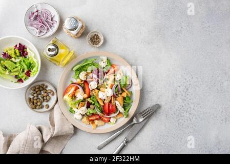 Panzanella salad with mozzarella cheese and capers on a plate, top view. Healthy italian vegetable tomato salad. Copy space for text or design or reci Stock Photo