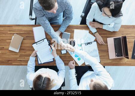Business people at their desk shake hands in handshake. business Stock Photo