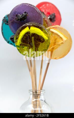 Colored lollipops with different berries and fruits inside in a bottle on a white background. Stock Photo