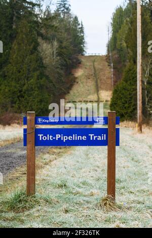 Blue and white King County signage for Tolt-Pipeline Trail along Kelly Road near Duvall in Washington State as the trail rises away in to the distance Stock Photo