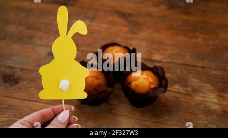 Yellow rabbit made of paper on a toothbrush. Hand holds Easter baking decor Stock Photo