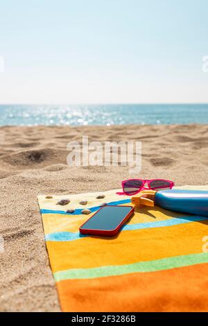 Towel, sunsreen, sunglasses and smart phone on the beach. Summer concept. Stock Photo