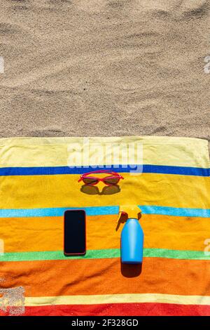 Towel, sunsreen, sunglasses and smart phone on the beach. Summer concept. Stock Photo