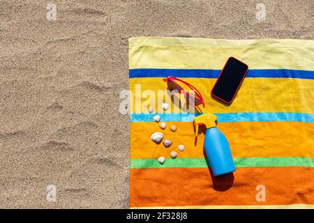 Towel, sunsreen, sunglasses and smart phone on the beach. Summer concept. Stock Photo