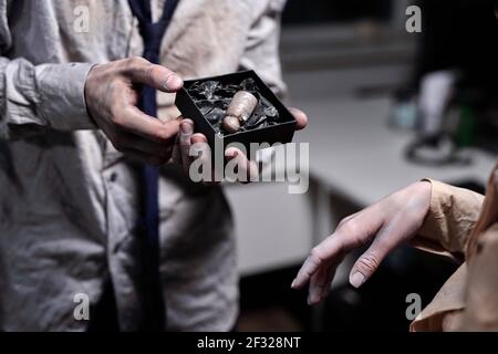 Hand of dead businessman holding small box containing cut finger with engagement diamond ring while offering it to zombie female Stock Photo