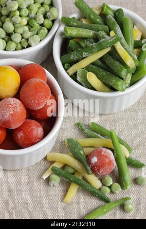 Frozen vegetables assorted in bowls isolated on white background, closeup, saving leftovers, food storage concept and eating meals at home concept Stock Photo