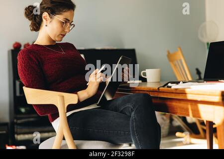 Female designer using graphic tablet for making new illustration while at home. Woman looking at the sketches on her digital tablet. Stock Photo