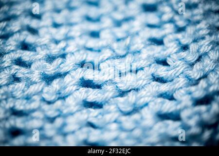 An extreme close-up shot with selective focus of a piece of deep blue knitted fabric. Stock Photo