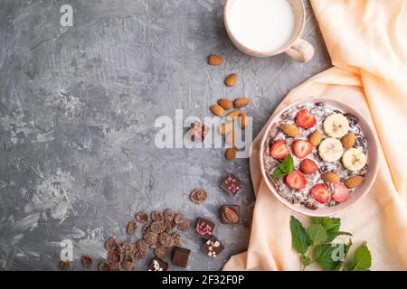 Chocolate cornflakes with milk, strawberry and almonds in ceramic bowl on gray concrete background and orange linen textile. Top view, flat lay, copy Stock Photo