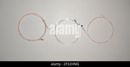 set of wound steel and bronze acoustic electric guitar strings rolled up and formed on isolated and white background. Stock Photo