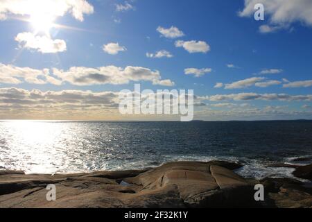 Panoramic view form the rocky coastline of Peggy's Cove, Nova Scotia, looking out over the Atlantic Ocean. Calm sea, blue sky with light clouds Stock Photo