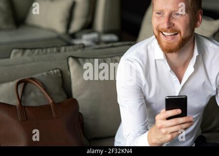 Happy young man using his smart phone at office Stock Photo