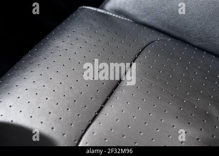 Close-up detail view of modern black perforated dotted ventilated luxury car seat. Part of dark vehicle interior. Auto detailing and leather polish Stock Photo