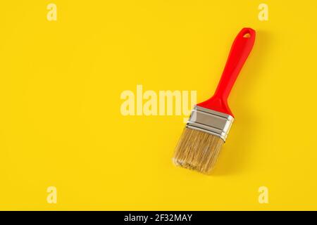 Paintbrush with red handle on yellow background. Stock Photo