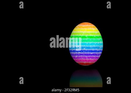 Easter egg painted with different rainbow colors, isolated on black bakcground. Stock Photo