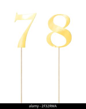 Shiny gold  topper paper cake numbers signs (seven, eight) on stick isolated on white background. Clipping path included. Stock Photo