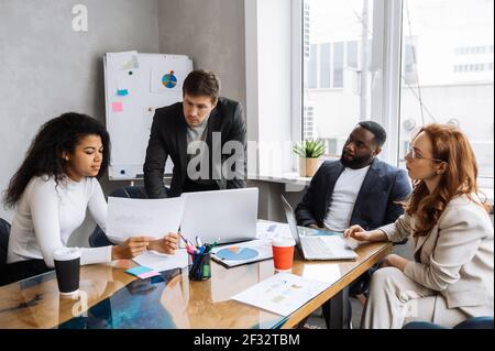 Serious business people on briefing meeting in office, working together on important financial report. Influential colleagues discussing ideas for corporate project, learning documents Stock Photo