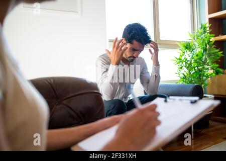 Psychologist taking notes during therapy session. Stock Photo