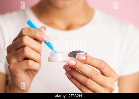 Young woman putting eye contact lens on her eyes Stock Photo