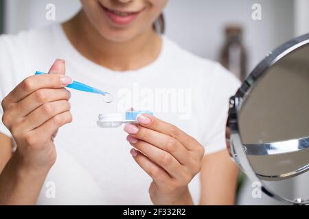 Young woman putting eye contact lens on her eyes Stock Photo