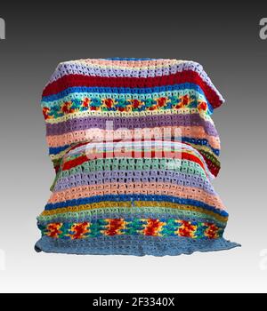 A vintage colorful broomstick stitch lace crochet blanket draped over a chair created by American textile artist Margaret Braaten (1914-2004). Stock Photo