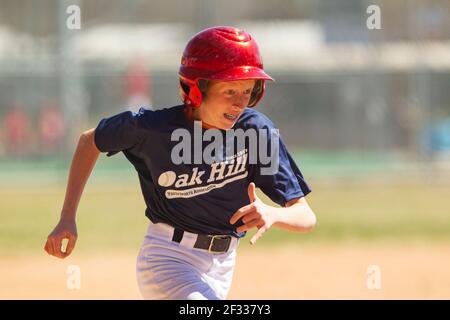 A red-headed teenage baseball player plays baseball in a youth league. Stock Photo