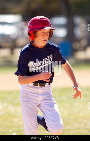 A red-headed teenage baseball player plays baseball in a youth league. Stock Photo