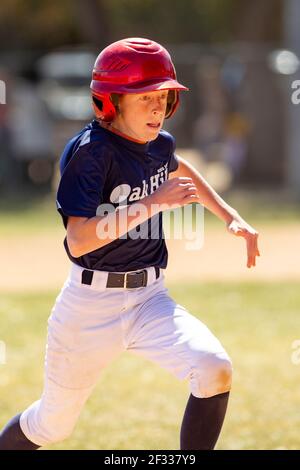 A red-headed teenage baseball player plays baseball in a youth league. Stock Photo