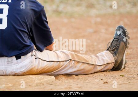 A dirty baseball runner sits on the base after being tagged out on a play. Stock Photo