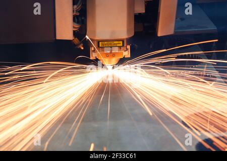 Industrial CNC laser cutting metal sheet with sparks. Selective focus. Stock Photo