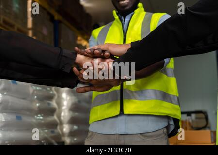Factory workers stacking hands together in warehouse or storehouse . Logistics , supply chain and warehouse business concept . Stock Photo