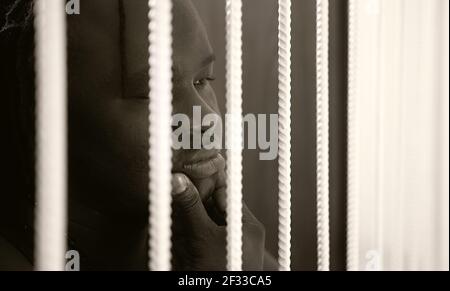 Jailed african american black man rubbing his chin behind bars. High quality photo Stock Photo