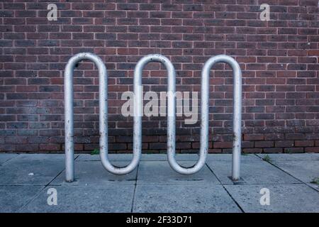 silver tube modern art bicycle resting place with a brick wall in the background Stock Photo