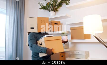 Happy young man with smiling cardboard box over his head dancing while moving in the new home. High quality photo Stock Photo