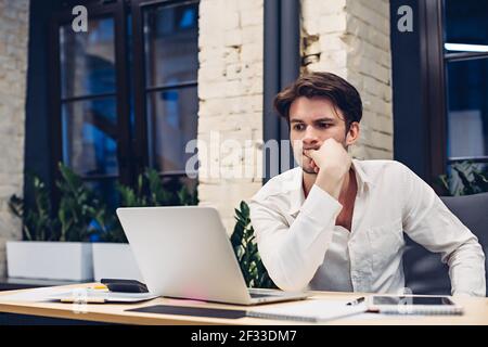 Thoughtful businessman working on laptop in office Stock Photo