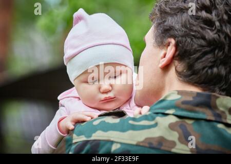 Military Dad goes to War and holds a sad one-year-old Daughter in his arms Stock Photo