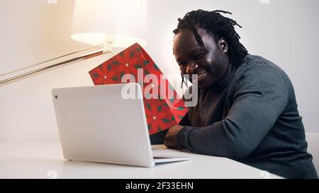 Young african american black man having a video call using laptop. Showing gift to his girlfriend. High quality photo Stock Photo