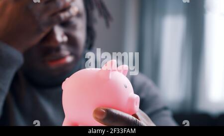 Upset african american man holding empty piggybank . High quality photo Stock Photo