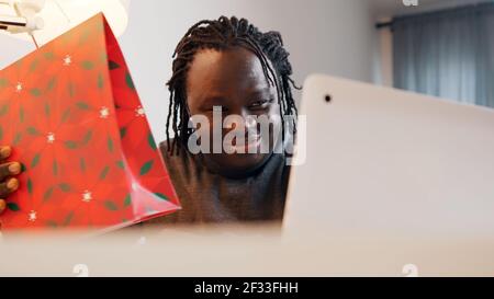 Young african american black man smiling while having video call. Online dating concept. Presenting the gift box. High quality photo Stock Photo