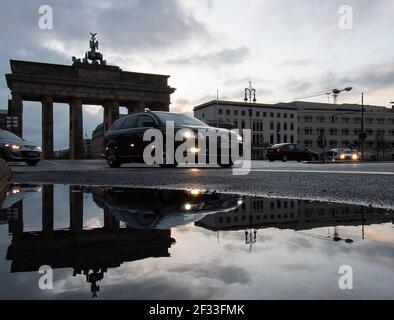 Berlin, Germany. 15th Mar, 2021. The Brandenburg Gate is reflected in a puddle of rain as vehicles pass by. Credit: Paul Zinken/dpa-Zentralbild/dpa/Alamy Live News Stock Photo
