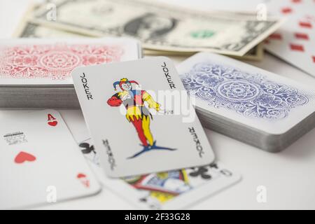 Joker card in the center of various playing cards turned both ways. Stock Photo